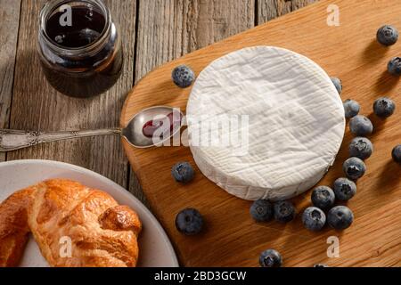 Camembert-Käse, Blaubeeren und Marmelade serviert zu einem frisch gebackenen Croissant Stockfoto