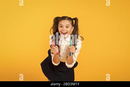 Happy Arts glücklichen kleinen Künstler. Happy girl Holding bunte Markierungen auf gelben Hintergrund. Fröhliches kleines Kind mit glücklichem Lächeln und Stifte. Genießen Sie Kunst und Kunsthandwerk. Stockfoto