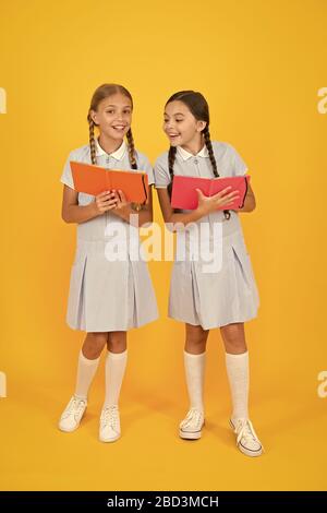 Schule Bibliothek. Pädagogische Bücher für Schulen. Bücher zu lesen. Homeschooling Konzept. Alphabetisierung Club. Süße Kinder holding Bücher auf gelben Hintergrund. Kleine Mädchen mit Lexikon oder Bücher der Kinder. Stockfoto