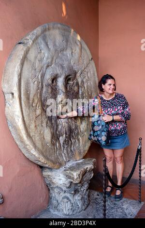 Tourist mit der Hand im Mund der Wahrheit (Bocca della Verità), Marienbasilika in Cosmedin/Basilika di Santa Maria in Cosmedin, Rom, Italien. Stockfoto