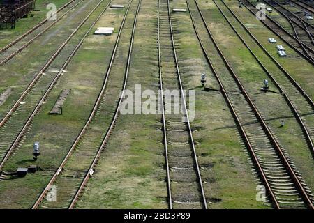 Leere Bahngleise von oben. Verlassene Bahngleise. Bahnschienen auf grünem Gras. Anhalten von Zügen während der Quarantäne. Stockfoto