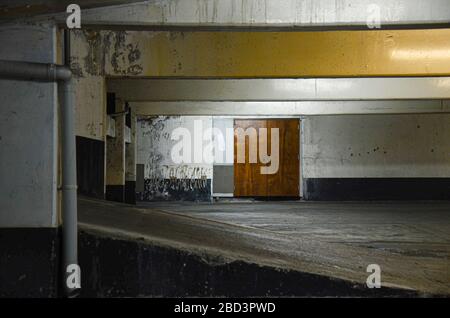 Schwach beleuchtete, leere Garage mit Holztür im Hintergrund Stockfoto