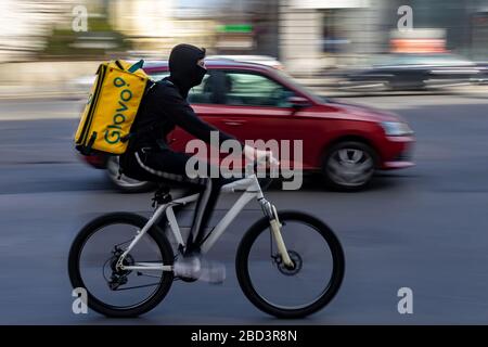 Bukarest, Rumänien - 17. März 2020: Ein Glovo-Kurier für die Lebensmittelzustellung mit Maske auf dem Fahrrad. Restaurants sind geschlossen und nur Lieferungen sind zulässig Stockfoto