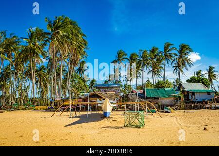 Ein Boot, das an einem sonnigen Nachmittag auf dem Sand von Nacpan Beach zur Wartung in El Nido, Philippinen, gebettet wurde Stockfoto