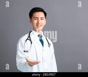 Portrait der männlichen asiatischen jungen Arzthand, die etwas zeigt Stockfoto