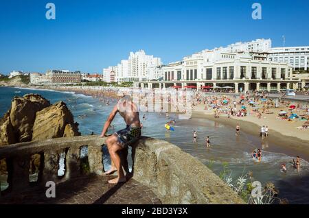 Biarritz, französisches Baskenland, Frankreich - 19. Juli 2019: EIN junger Mann blickt auf La Grande Plage, den größten Strand der Stadt. Art déco' Style Casino of Stockfoto
