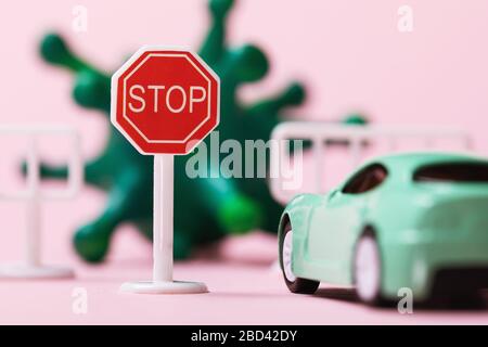 Spielzeug-Straßenschild, Auto und Coronavirus, Nahaufnahme. Das Konzept des Reiseverbots aufgrund der Kovid-19-Pandemie Stockfoto