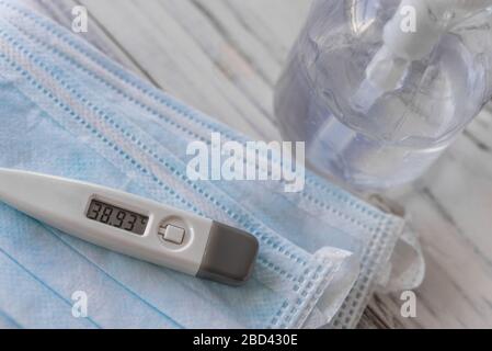 Thermometer mit Fieber, Händedesinfektionsmittel und Gesichtsmasken. Symptome des Coronavirus. Stockfoto