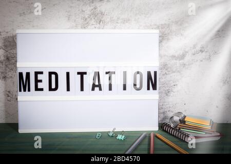 Meditation. Freizeit, psychische Gesundheit und Yoga-Konzept. Weißer Leuchtkasten auf einem Holztisch Stockfoto