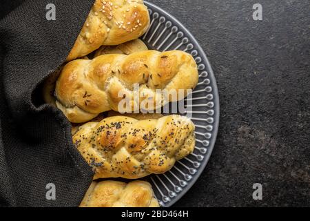 Leckere Flechtbrötchen auf schwarzem Küchentisch. Draufsicht. Stockfoto