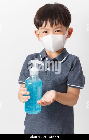 Asiatischer Junge, der einen Schutz mask​ trägt und eine Flasche Alkoholgel zur Reinigung der Baby-Hände hält, um eine Infektion des Covid-19-Ausbruchs zu verhindern. Stockfoto
