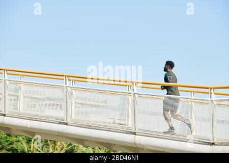 Junger schwarzer Mann, der am Morgen entlang der Brücke läuft Stockfoto
