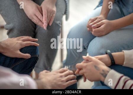 Nahaufnahme von Menschen, die in einem Kreis nahe beieinander sitzen Stockfoto