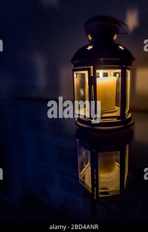 Nahaufnahme einer Laterne mit einer leuchtenden Kerze reflektiert Auf einem polierten Holztisch Stockfoto