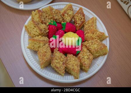 In einer weißen Kunststoffplatte befindet sich ein brauner und roter Kuchen. Ein Kuchen in Form einer rechteckigen Baklava Stockfoto