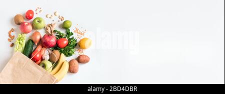Lieferung gesunder Lebensmittel Hintergrund. Vegane vegetarische Speisen in Papiertüten Gemüse und Obst, Nüsse und Körner auf Weiß, Kopierraum, Banner.Lebensmittelschopp Stockfoto