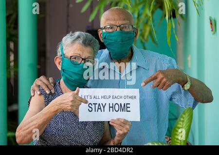 Ein älteres Paar, das Gesichtsmaske und Brille trägt und einen Heimaufenthalt in Sing hält Stockfoto