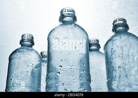 Klare Plastikflaschen mit Wassertropfen in monochromer blau-weißer Hintergrundbeleuchtung. Konzept der globalen Erwärmung, Klimawandel und Plastikverschmutzung Ozean. Stockfoto
