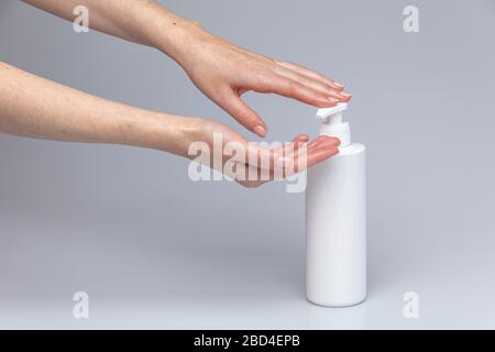 Weiße Menschenhände waschen sich mit grünem Schaum Marseilles Seife isoliert vor einem grauen Hintergrund mit strukturierenden Lichtern und Schatten Stockfoto