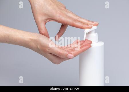 Weiße Menschenhände waschen sich mit grünem Schaum Marseilles Seife isoliert vor einem grauen Hintergrund mit strukturierenden Lichtern und Schatten Stockfoto