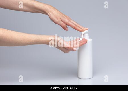 Weiße Menschenhände waschen sich mit grünem Schaum Marseilles Seife isoliert vor einem grauen Hintergrund mit strukturierenden Lichtern und Schatten Stockfoto