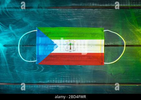 Medizinische Maske zum Schutz vor durch die Luft übertragenen Krankheiten, in der Nationalflaggen Äquatorial-Guineas auf schwarzem Grund in blaugrünem Rauch gemalt. Ich Stockfoto
