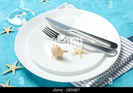 Tischeinstellung mit Seashells und Starfishes auf türkisfarbenem Hintergrund, Nahaufnahme Stockfoto