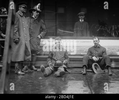 Feuerwehrleute saßen auf dem Bürgersteig, nachdem sie einen Brand in einem U-Bahn-Tunnel in New York City bekämpft hatten, der in der Nähe der West 55th Street und des Broadway am 6. Januar 1915 stattfand Stockfoto