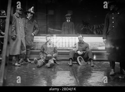 Feuerwehrleute saßen auf dem Bürgersteig, nachdem sie einen Brand in einem U-Bahn-Tunnel in New York City bekämpft hatten, der in der Nähe der West 55th Street und des Broadway am 6. Januar 1915 stattfand Stockfoto