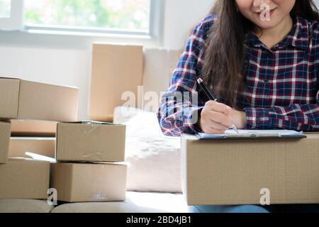 Junge Frau Unternehmer, auf dem Sofa sitzen und arbeiten zu Hause. Die Aufnahme der Jahresumsatz und die Planung auf Strumpf Produkte zur Lieferung Versand onl Stockfoto