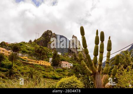 Roques de Pedro und Petra hinter einem wunderschönen Kaktus, der vom Tal in La Hermigua auf La Gomera aus gesehen wird. April 2019. La Gomera, Santa Cruz de Tenerif Stockfoto