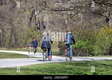 Das öffentliche Leben in Zeiten der Coronavirus-Pandemie am 5. April 2020 im Englischen Garten in München. Freizeitsportler, Radfahrer im Park. Das frühlingshafte Wetter treibt die Bevölkerung in die frische Luft, immer mit der notwendigen Entfernung aufgrund einer Infektion mit dem Corona-Virus. Ausstiegsbeschränkungen, Kontaktsperre. Weltweite Verwendung Stockfoto