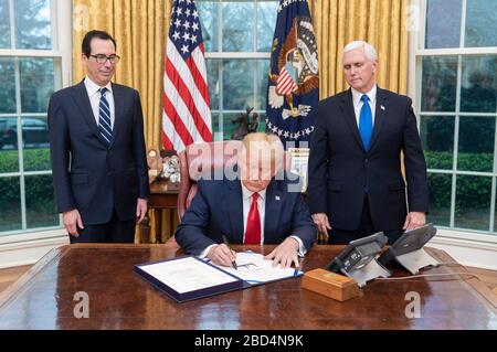 Der Resident Donald J. Trump wird von Vizepräsident Mike Pence und Finanzminister Steven Mnuchin ernannt, als er im Oval Office des Weißen Hauses H.R. 6201, dem Families First Coronavirus Response Act, am Mittwoch, 18. März 2020, unterschreibt. Stockfoto