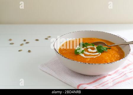 Kürbis- und Karottensuppe mit Sauerrahm und Petersilie. Vegetarische Suppe. Gesundes Essen Konzept. Stockfoto