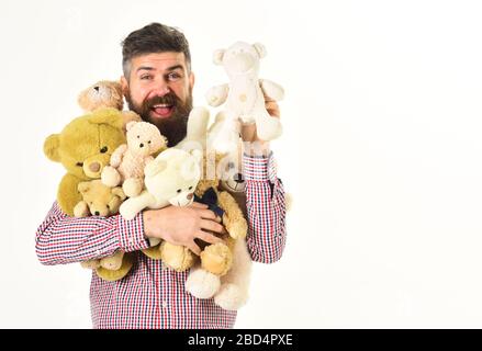 Mann mit fröhlichen Gesichtsumarmungen umarmt Teddybären, kopiere Platz. Macho mit Bart hält Plüschspielzeug oder Teddybären, isoliert auf weißem Hintergrund. Ewiges Kinderkonzept. Hipper fühlt sich wie Kind mit Spielzeughaufen an. Stockfoto