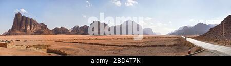 Sieben Säulen der Weisheit, wie sie im Eingang zu Wadi Rum gesehen wurden, schützten das Gebiet vor dem Besucherzentrum. Kleine Geländewagen im Vordergrund geparkt Stockfoto