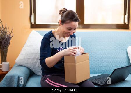 Happy Woman öffnet ihr online bestelltes Paket. Konzept des zufriedenen Kunden nach einer Online-Bestellung Stockfoto