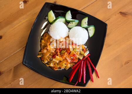 Hausgemachtes veganes süßes und saures Gemüse rühren mit Reis auf schwarzem Teller, Draufsicht Stockfoto