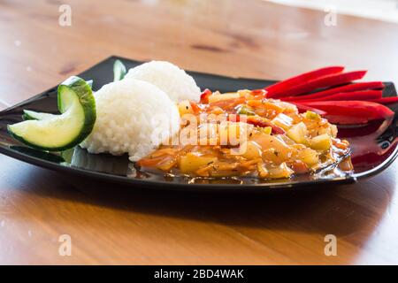 Hausgemachtes veganes süßes und saures Gemüse rühren mit Reis auf schwarzem Teller Stockfoto