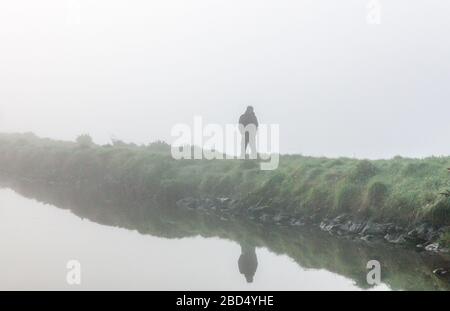 Carrigaline, Cork, Irland. April 2020. Ein Mann spaziert im Nebel am frühen Morgen durch den Gemeindepark in Carrigaline, Co. Cork, Irland. Unter behördlichen Einschränkungen ist die Ausübung nur innerhalb von 2 Kilometern von Ihrem Zuhause und nur mit Personen aus Ihrem eigenen Haushalt gestattet. - Credit; David Creedon / Alamy Live News Stockfoto