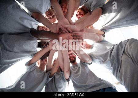 Lächelnde junge Leute, die einen hohen Turm aus ihren Händen machen Stockfoto