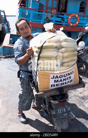 dh Port of Benoa BALI INDONESIA Indonesian lokaler Mann, der heissen Mais auf dem Motorrad aus Asien verkauft Stockfoto