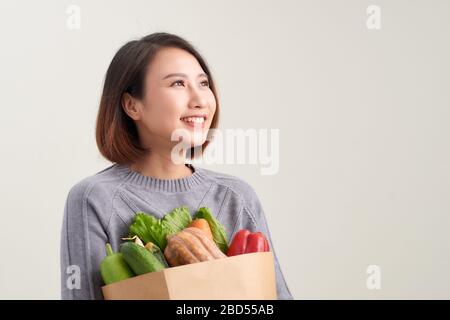 Stets gut gelaunte Frau hält eine Einkaufstasche voller Lebensmittel Stockfoto
