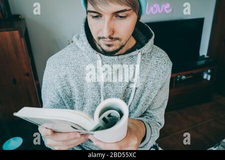 Junger Mann liest ein Buch in seinem Haus Stockfoto
