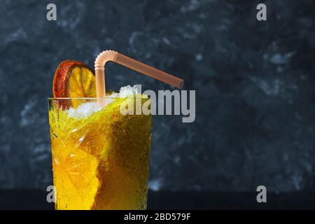 Helles, sommerliches erfrischendes Getränk in einem hohen Glas mit zerkleinerten Eis auf dunklem Hintergrund. Draufsicht mit Kopierbereich. Oben Stockfoto