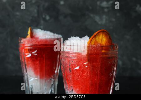 Helles, sommerliches erfrischendes Getränk in einem hohen Glas mit zerkleinerten Eis auf dunklem Hintergrund. Draufsicht mit Kopierbereich. Oben Stockfoto
