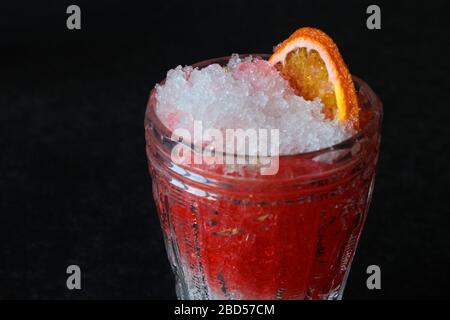 Helles, sommerliches erfrischendes Getränk in einem hohen Glas mit zerkleinerten Eis auf dunklem Hintergrund. Draufsicht mit Kopierbereich. Oben Stockfoto