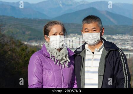 Paare mittleren Alters tragen eine weiße Maske zum Schutz gegen Coronavirus COVID-19 (SARS-COV-2) und andere Infektionskrankheiten. Blick auf die Kamera. Stockfoto