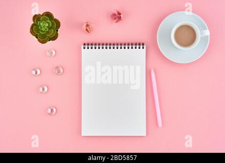 Leerer Notizblock weiße Seite und Tasse Kakao auf pinkfarbenem Schreibtisch. Draufsicht, flacher Lay Stockfoto