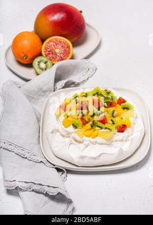 Hausgemachtes Pavlova Kuchen Dessert mit Baiser und frischen Obstscheiben aus Kiwi, Mango, Ananas und Blutorange. Selektiver Fokus. Stockfoto